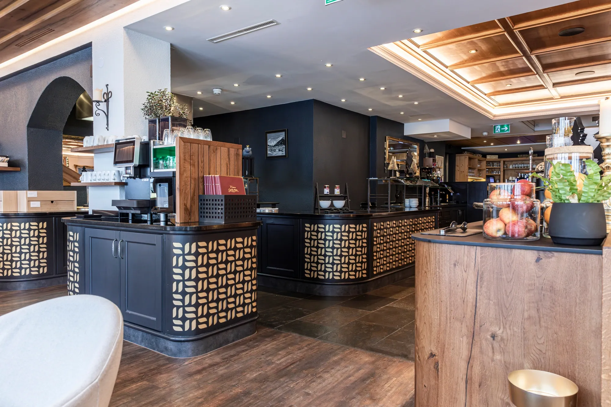 Buffetbereich im Speisesaal mit dunklen Theken, Kaffeestation und Obst.
