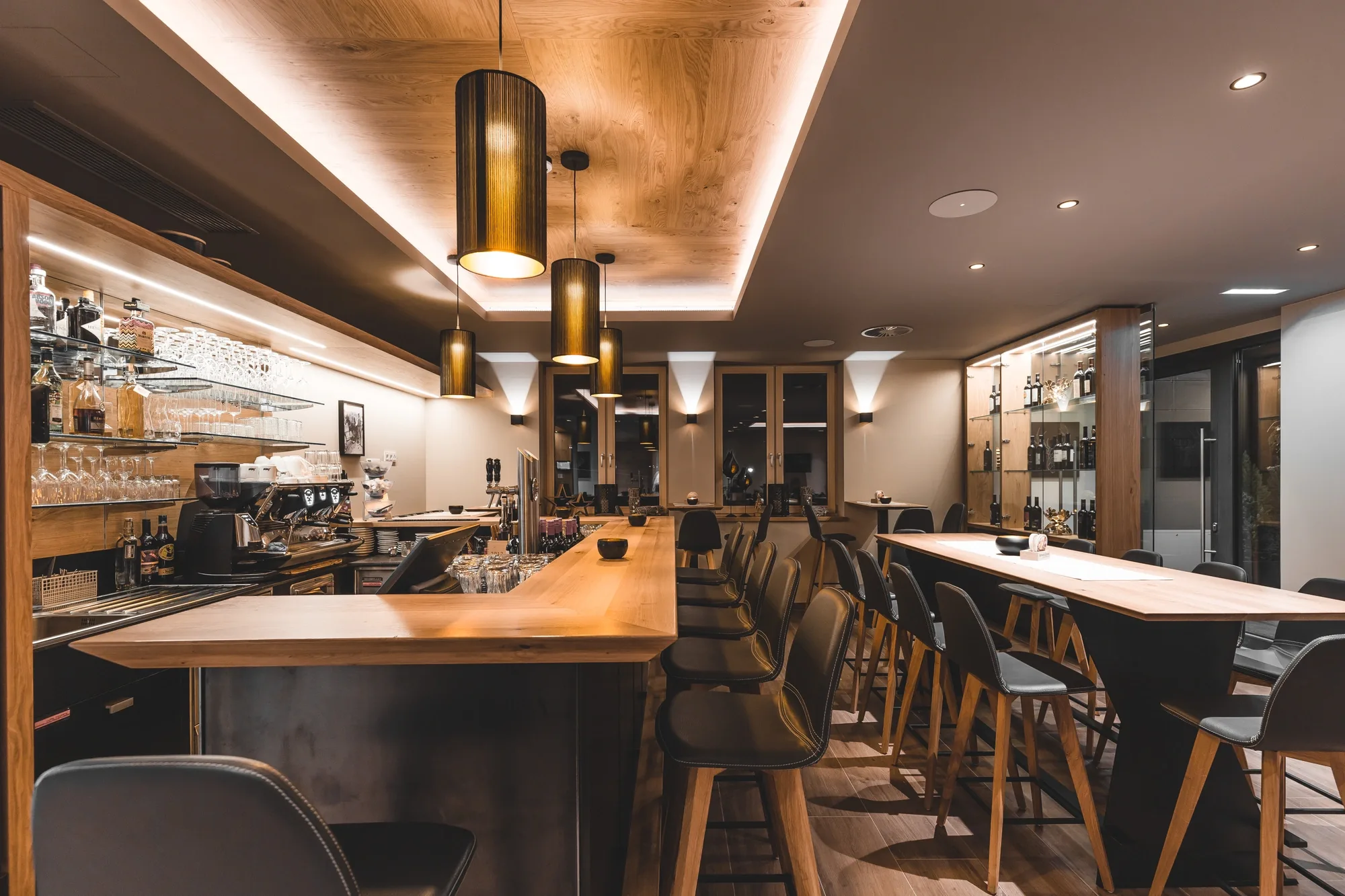 Barbereich der Mathon Lounge mit Holztheke, Barhockern und Pendelleuchten